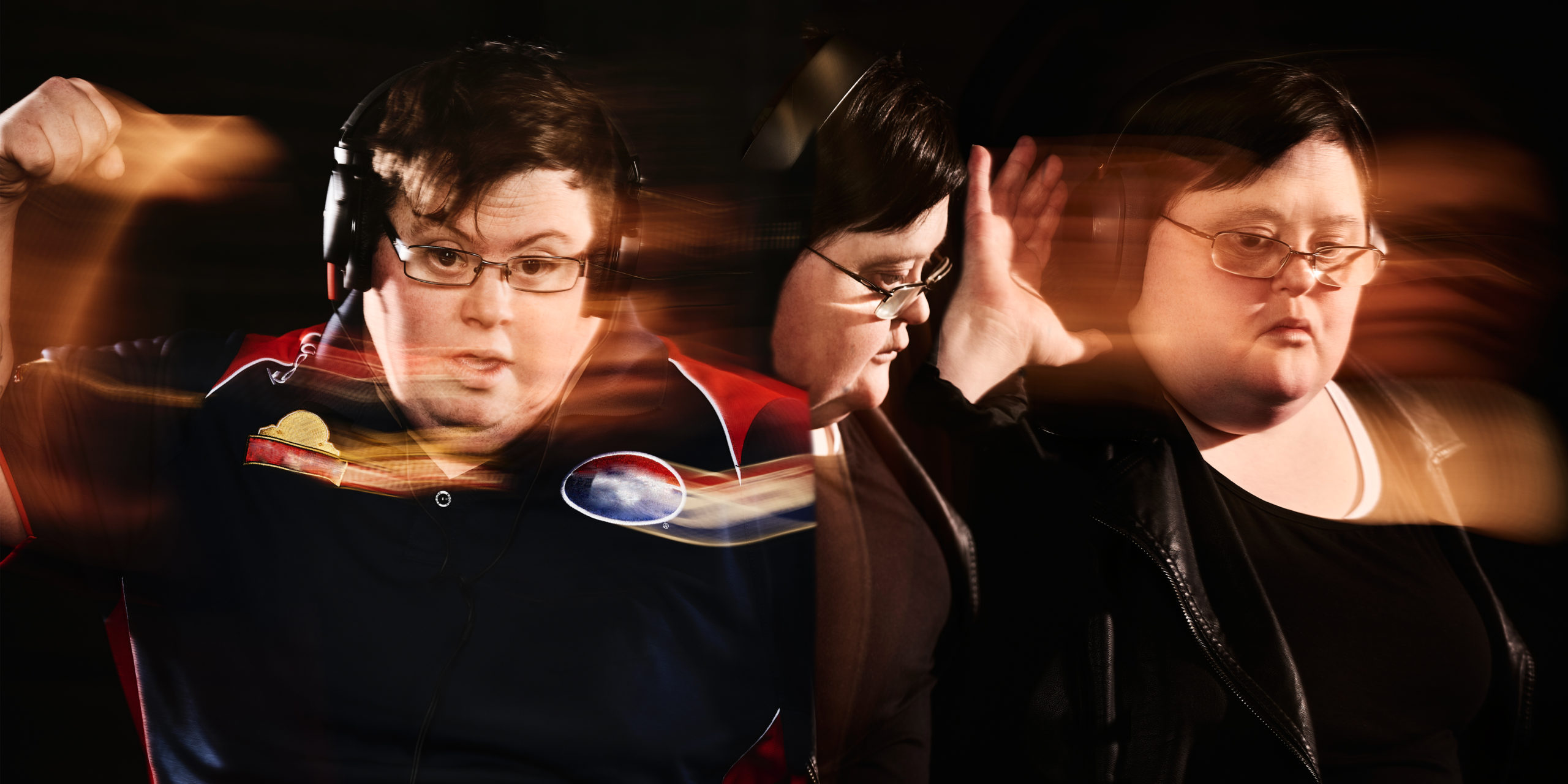 The head and shoulders of three figures wearing headphones are against a black background. The photo has image blur indicating the movement of the figures. One figure's arm is swinging while another has a hand cupped to their ear.